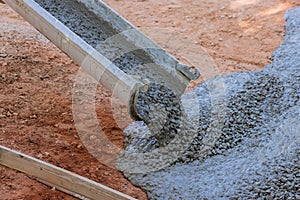 The concrete is being poured in the course of paving a driveway at a construction site on the site of a near new home.