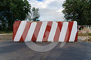 Concrete block with red and white striped lines as a roadblock, traffic is prohibited and road works, the road is closed for