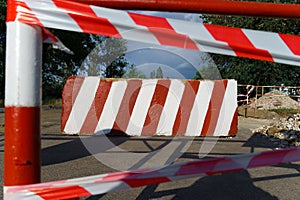 Concrete block with red and white striped lines as a roadblock, traffic is prohibited and road works, the road is closed for