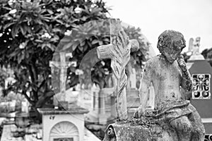 Concrete boy on top of tombstone at cemetery