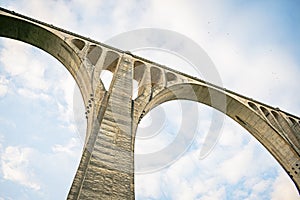 Concrete bridge over a cloudy background with several eyes in its structure to reinforce each large arch