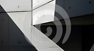 Concrete building facade with sharp angular shadows creating a geometric