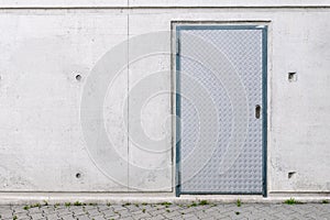 Concrete building wall facade with armored steel diamondplate textured door. Undeground safety shelter bunker entrance