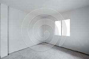 Concrete cement floor with white wall and window. Under construction empty room interior