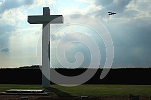 Concrete cross with cloudy sky and sport plane