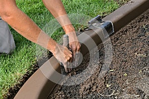 Concrete curb edging being shaped for smoothness in a flower bed photo