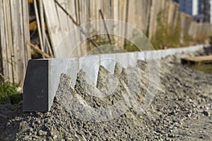 Concrete curb installation works at road construction site. Shallow DOF.