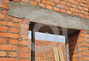 Concrete door lintel installation with metal holders. Door concrete lintel on brick unfinished house construction.