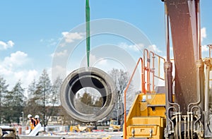 Concrete drainage pipe lifted by excavator during deep drainage works on construction site