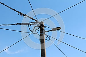 Concrete electrical utility pole with modern LED public light and multiple electrical wires going in all directions