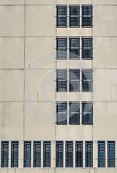 The concrete facade of a prison. The windows are fitted with bars so that the prisoners cannot escape. The windows are placed