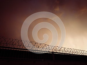 Concrete fence with barbed wire against the sky. Prison concept