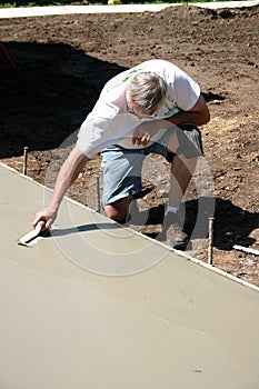 Concrete Finisher with Trowel Kneeling photo