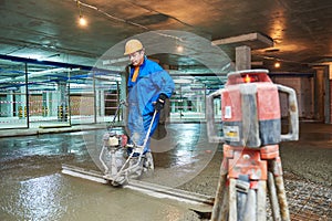 Concrete floor construction. Worker with screeder