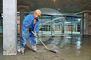 Concrete floor construction. Worker with screeder photo