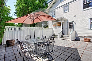 Concrete floor cozy patio area with table set and patio umbrella.