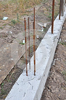 The concrete footer for new fence mounting. Fence footings. Close up on reinforced concrete footing for fence foundation with