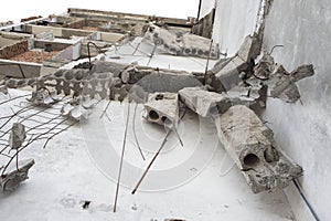 Concrete fragments hang on the reinforcement on the wall of the destroyed building. Background. Bottom view