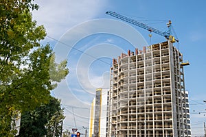 Concrete frame of tall apartment building under construction and tower crane in a city