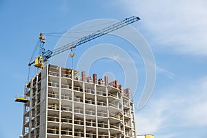 Concrete frame of tall apartment building under construction and tower crane in a city