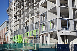 Concrete high-rise building under construction with white tower crane