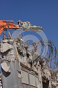 Concrete industrial building demolition - building destruction with machinery - blue sky - stock