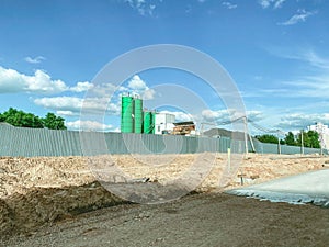 A concrete knot of bright, green color stands behind a building fence. production of concrete at the construction site. high