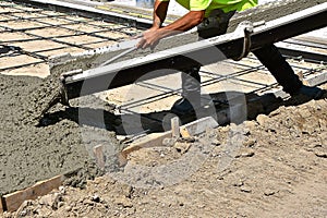 Concrete laborer worker pushes concrete off the chute