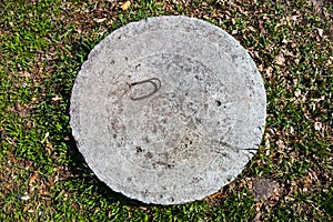 Concrete manhole cover in the grass