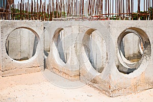 A concrete manhole prepared for use in drainage work. The large circular holes in the concrete manhole are intended for water pipe