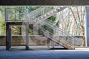 Concrete and metal stairs in covered parking lot with winter branches and green streetlamps in distance