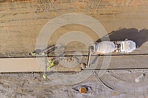 An concrete mix truck pouring cement at a construction site during the workers pouring of cement for sidewalk