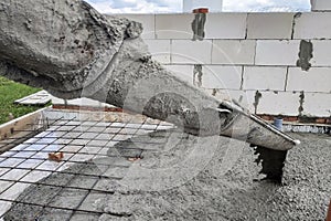 The concrete mixer feeds cement through the gutter to pour the concrete slab, sewer pipes are visible