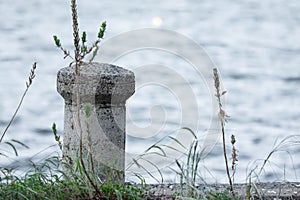 Concrete mooring bollard with a rope at a dock.