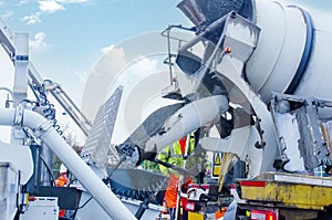 Concrete is offloaded from a concrete mixer into a concrete pump. Loading wet concrete