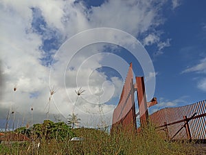 Concrete outdoor bridge with red fences on blue summers sky background.