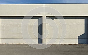 Concrete panel facade with a column in the middle. Aspalth road in front.