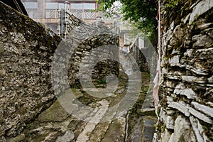 Concrete path between ancient stone walls on slope