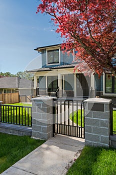 Concrete pathway and metal gate in front of residential house.