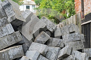 Concrete paving stones piled up in a disorderly pile at a construction site, working on paving a driveway.