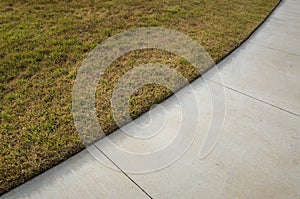 A concrete pedestrian footpath with a perfect lawn edge. Concept of garden landscaping, lawn edging, and grass maintenance.