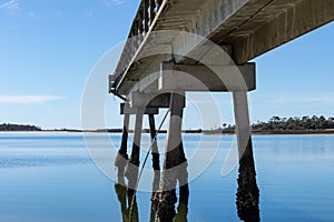 Concrete pier encrusted with barnacles extending into still blue waters, Tybee Island Georgia