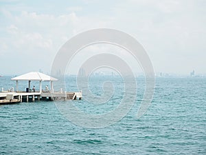 Concrete pier on sea/ocean with blue sky background .