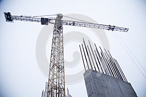 Concrete pillars on industrial construction site. Building of skyscraper with crane, tools and reinforced steel bars