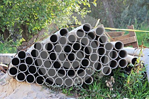 concrete pipes are stacked on the ground next to the construction of a house. Underground communications for laying