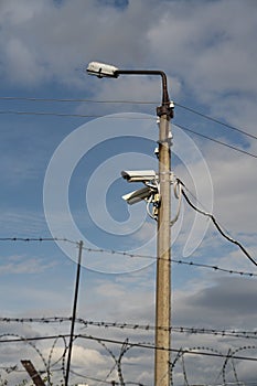 Concrete pole lantern with CCTV cameras against the blue sky.