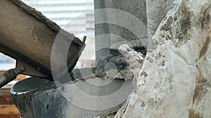 Concrete is poured from a concrete mixer into container on construction site.