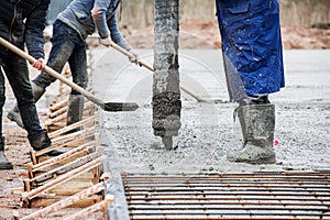 concrete pouring from a hose by workers at a shallow depth of field