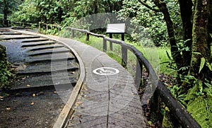 Concrete ramp way with wooden handrails and disabled sign for support wheelchair disabled people in the park