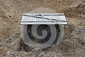 Concrete ring as a storm drain in the roadway during construction. Covered with a wooden shield